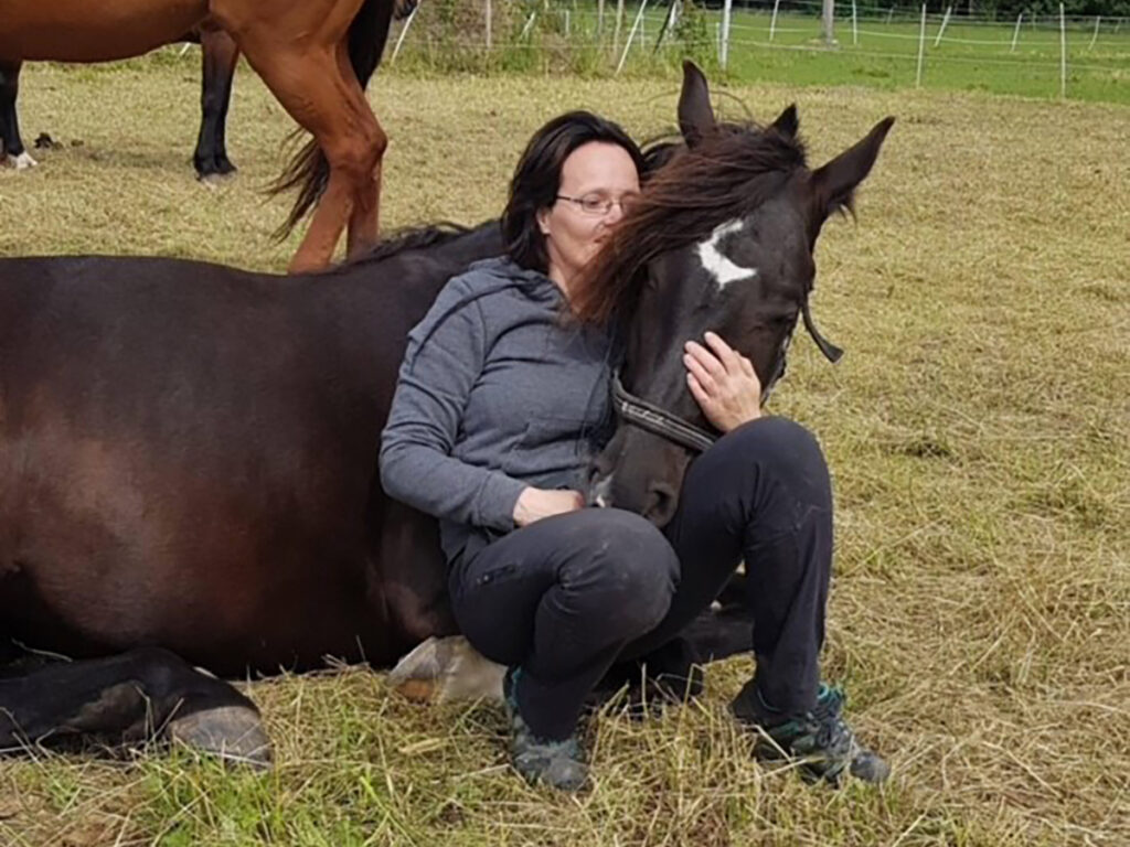 Monica fra Dalebro gård lener seg på en hest