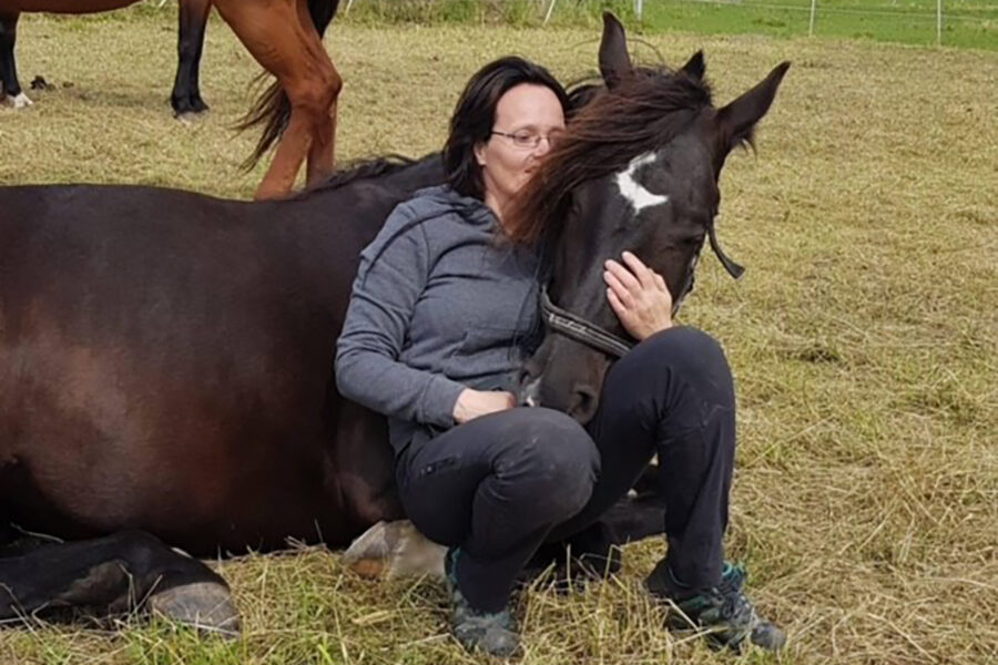 Monica fra Dalebro gård lener seg på en hest