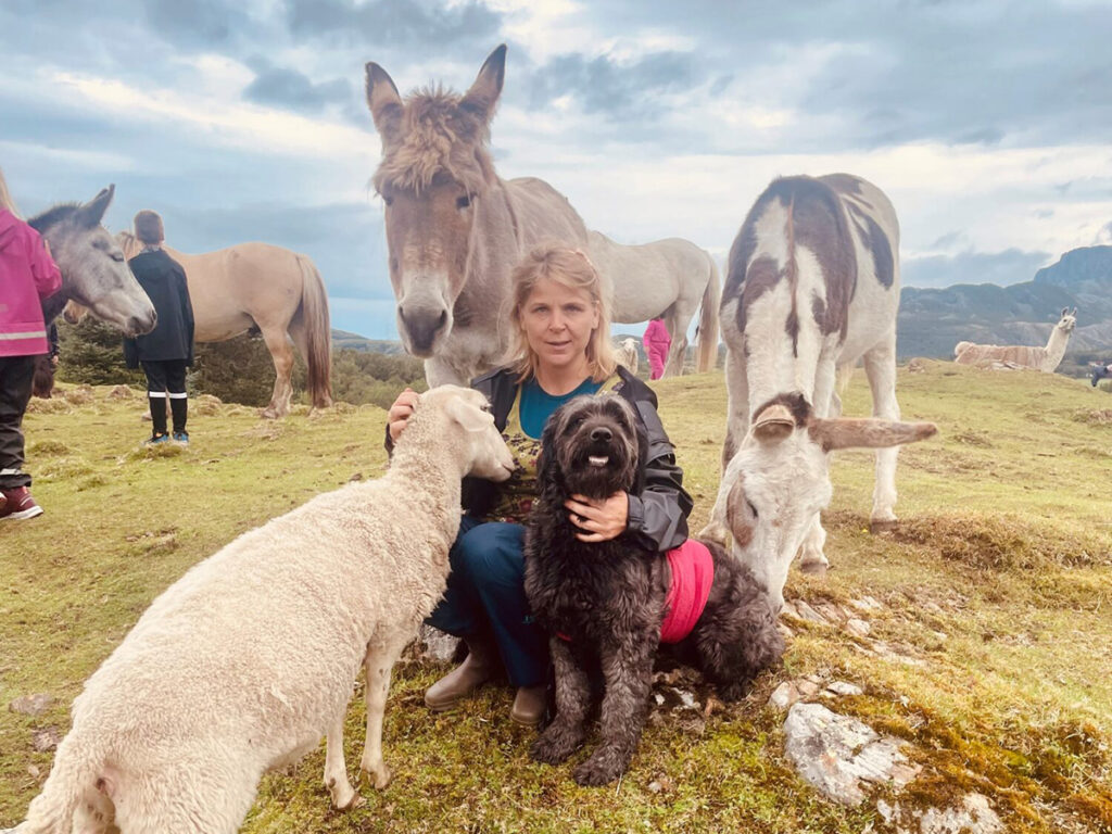 Lene-Isolde fra Humlehagen kulturgård omringet av diverse gårdsdyr