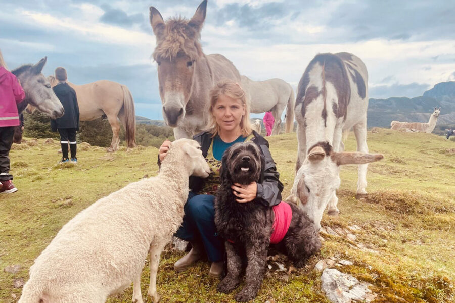 Lene-Isolde fra Humlehagen kulturgård omringet av diverse gårdsdyr